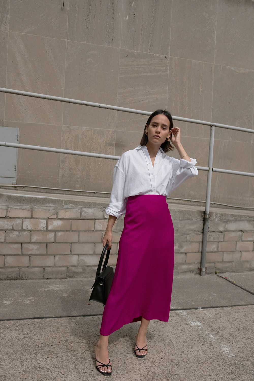 Nisi is wearing: White shirt – & Other Stories, Fuchsia skirt – Massimo Dutti, Le Grand Chiquito bag – Jacquemus, Strappy sandals – Mango, Dinner Date earrings – All Blues