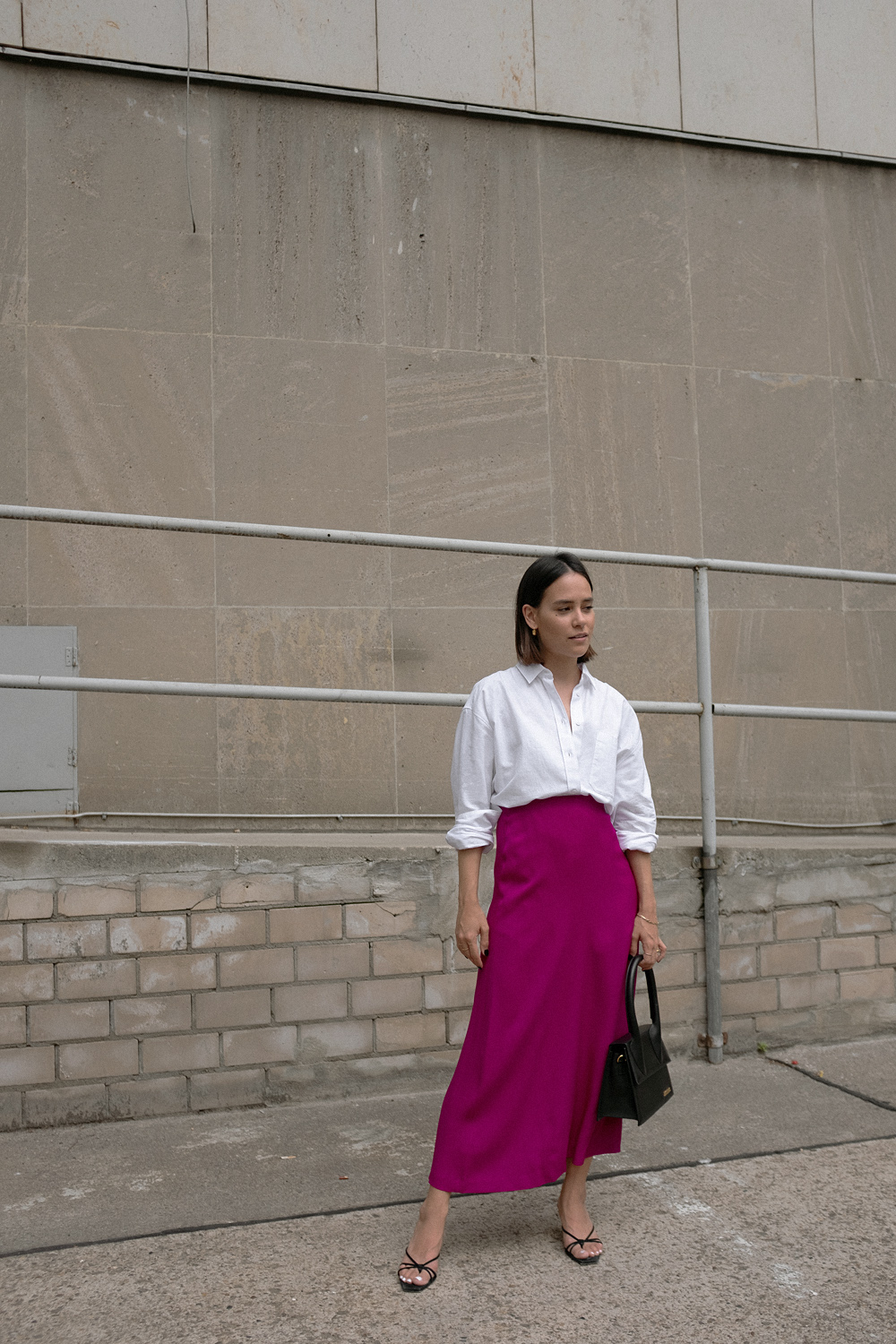 Nisi is wearing: White shirt – & Other Stories, Fuchsia skirt – Massimo Dutti, Le Grand Chiquito bag – Jacquemus, Strappy sandals – Mango, Dinner Date earrings – All Blues