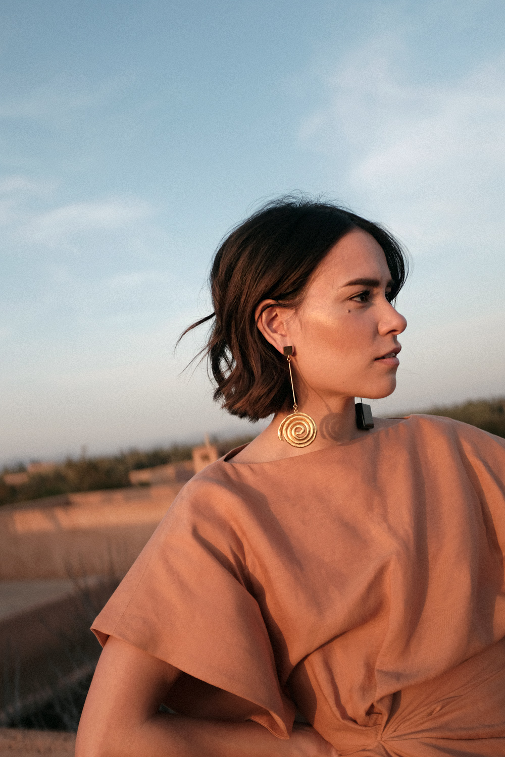 Nisi is wearing: Jacquemus La Robe Salvador dress and Le Carre earrings, The Row Chocolate Sandals in Morocco