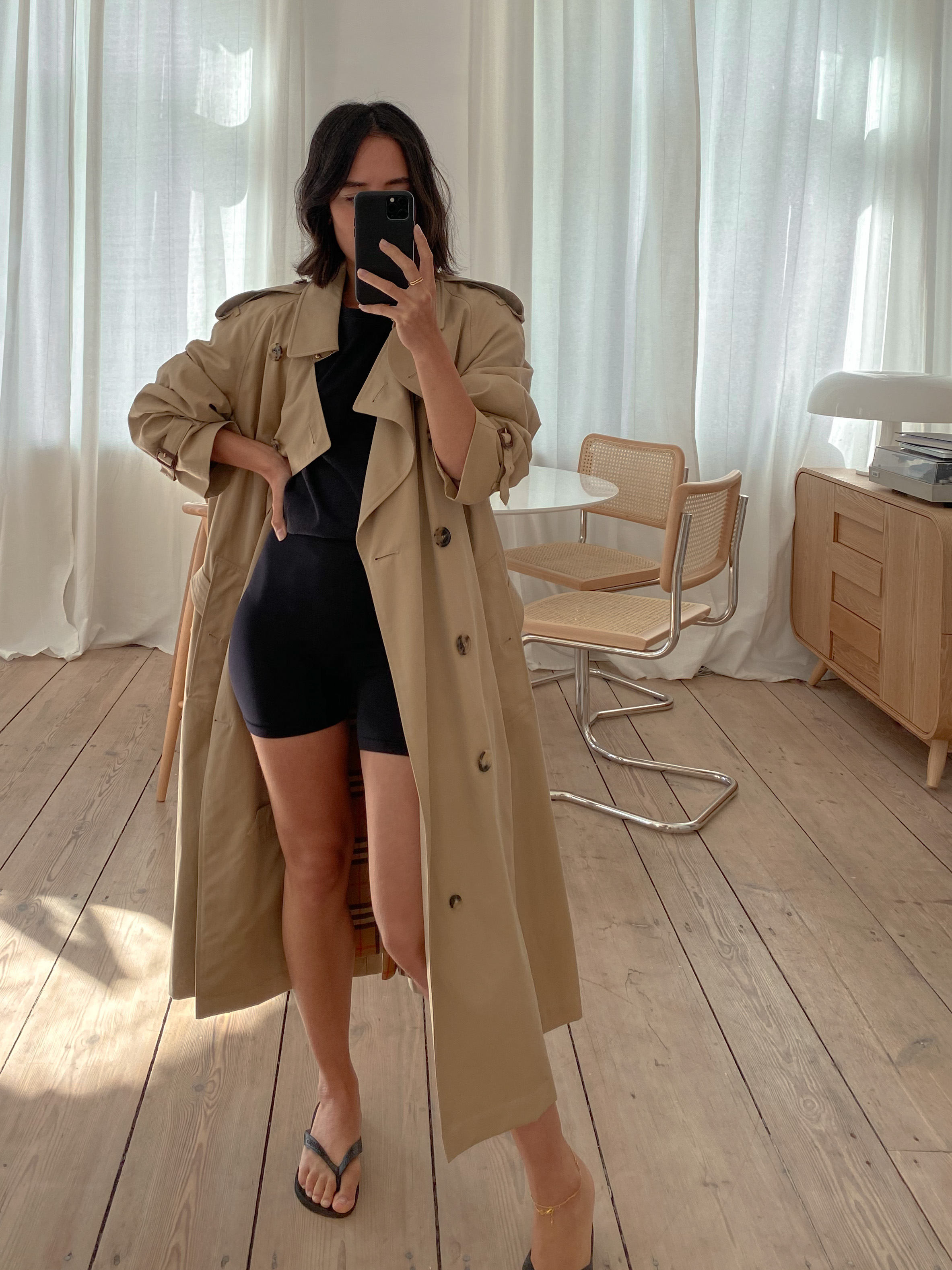 Nisi is wearing: Trenchcoat – Burberry, Cycling shorts – Arket, T-Shirt – Uniqlo, Flip Flops – Havaianas, Anklets – Missoma