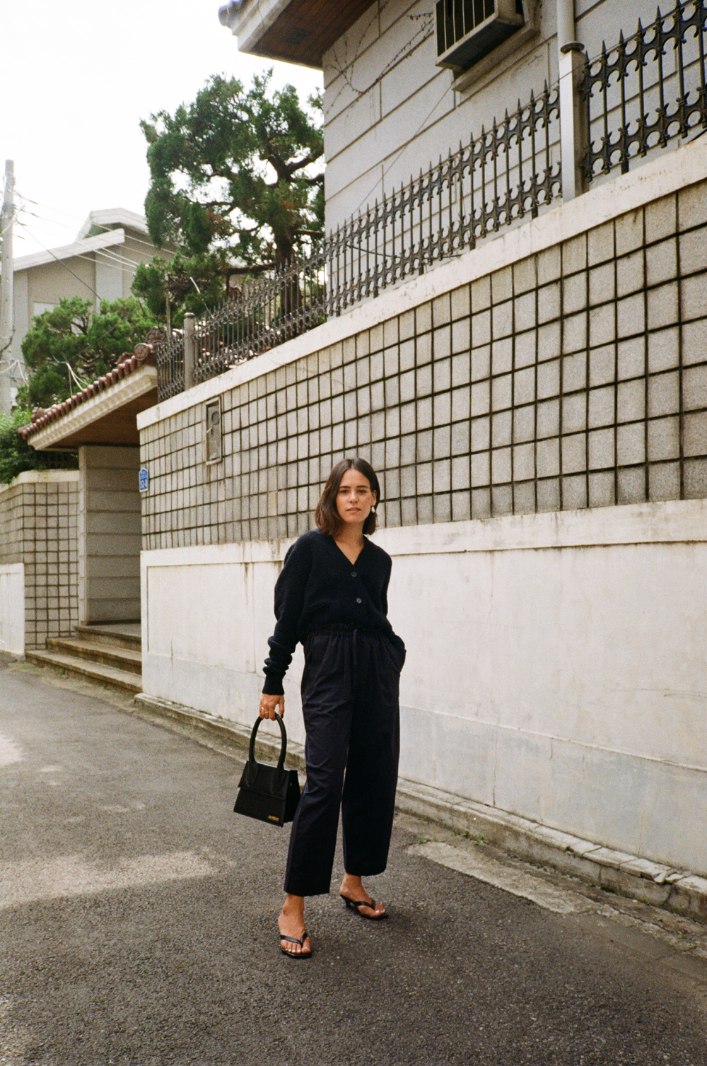 Céline Baroque Pearl earrings, Jacquemus Le Grand Chiquito bag, Totême Heeled Flip Flops, Arket Navyblue wool cardigan and Drawstring trousers