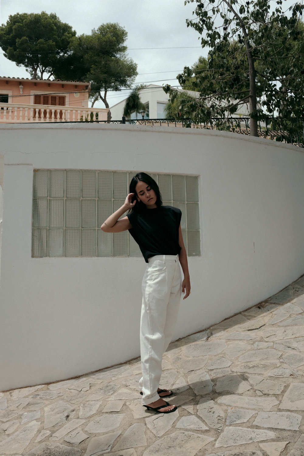 Nisi is wearing: Padded muscle shirt EDITED THE LABEL, White denim jeans EDITED THE LABEL, Flip flop heels TOTÊME, Fat Snake ring in silver ALL BLUES, Fat gold ring DAPHINE