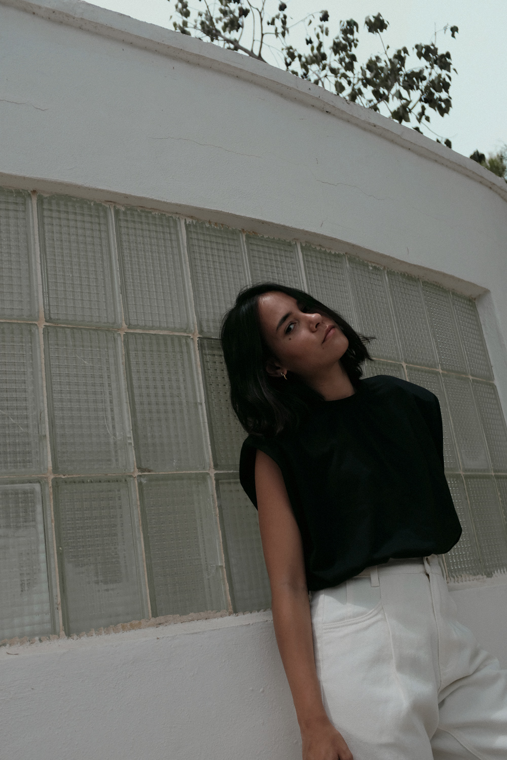 Nisi is wearing: Padded muscle shirt EDITED THE LABEL, White denim jeans EDITED THE LABEL, Flip flop heels TOTÊME, Fat Snake ring in silver ALL BLUES, Fat gold ring DAPHINE