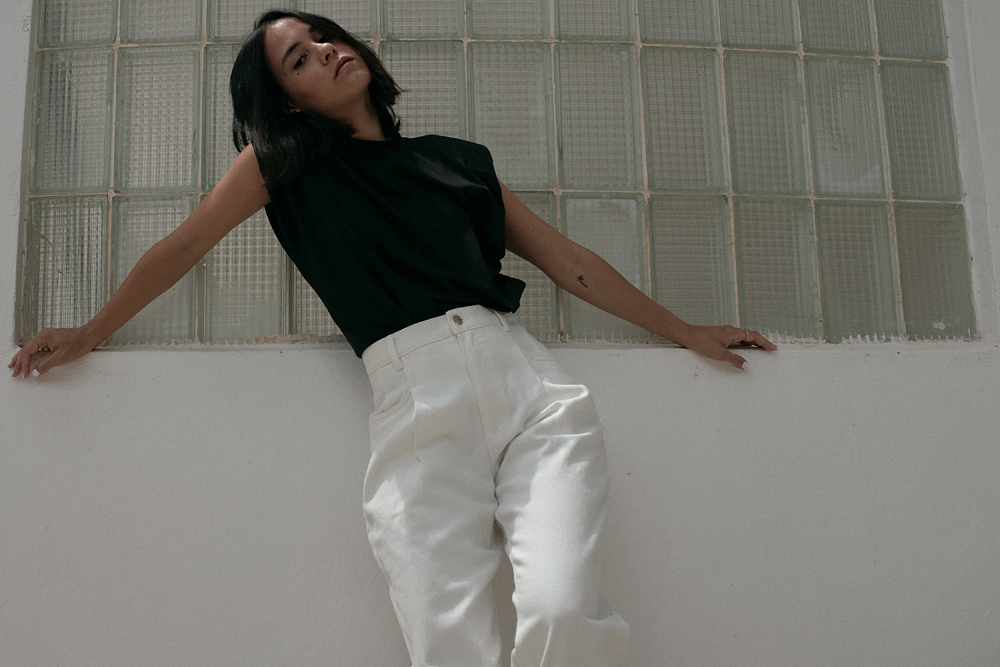 Nisi is wearing: Padded muscle shirt EDITED THE LABEL, White denim jeans EDITED THE LABEL, Flip flop heels TOTÊME, Fat Snake ring in silver ALL BLUES, Fat gold ring DAPHINE