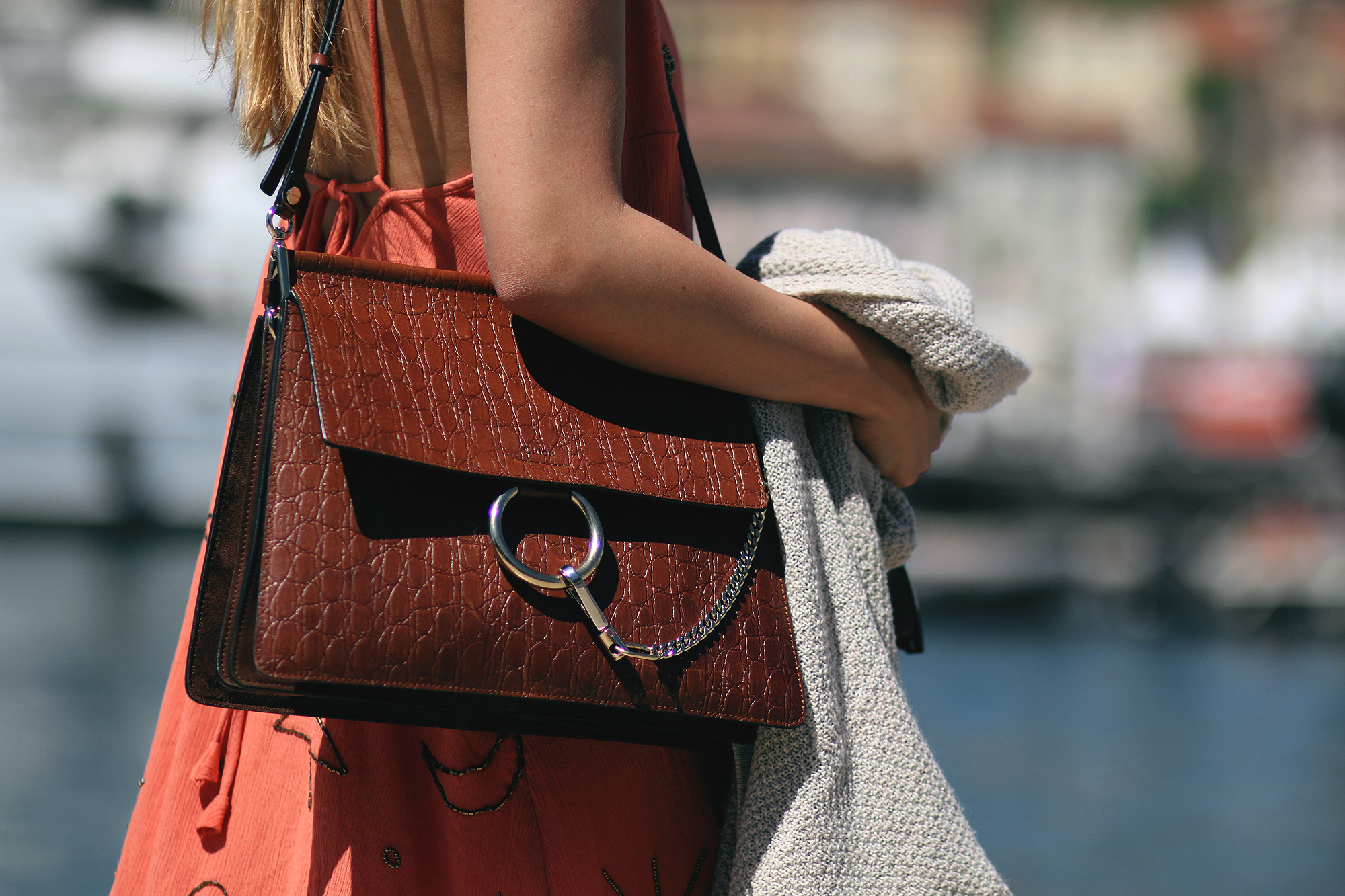 Desi is wearing: Embellished summer dress, cardigan, Cloé Faye bag, Hemès Oran Sandals, Ray-Ban Wayfarer sunglasses
