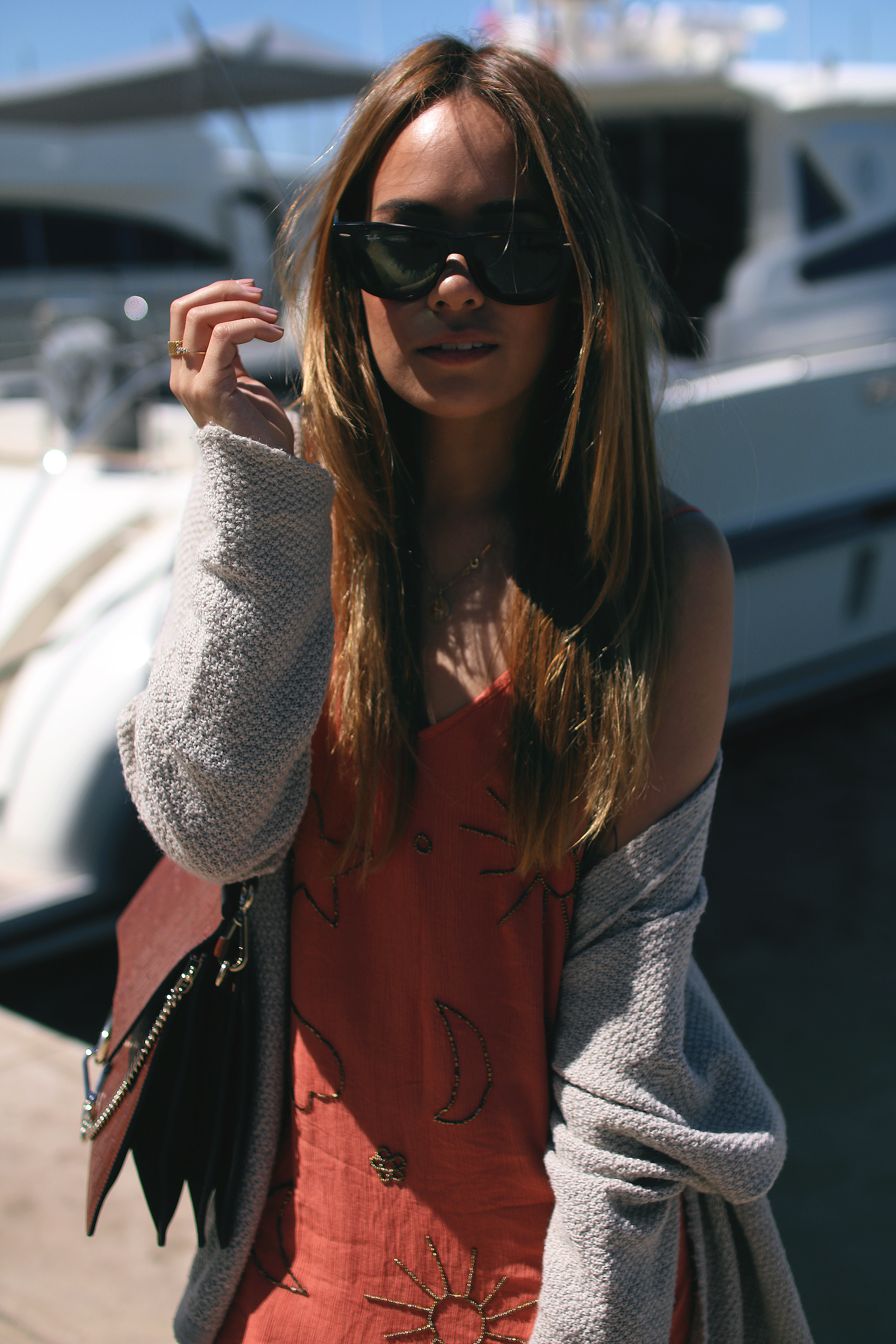 Desi is wearing: Embellished summer dress, cardigan, Cloé Faye bag, Hemès Oran Sandals, Ray-Ban Wayfarer sunglasses