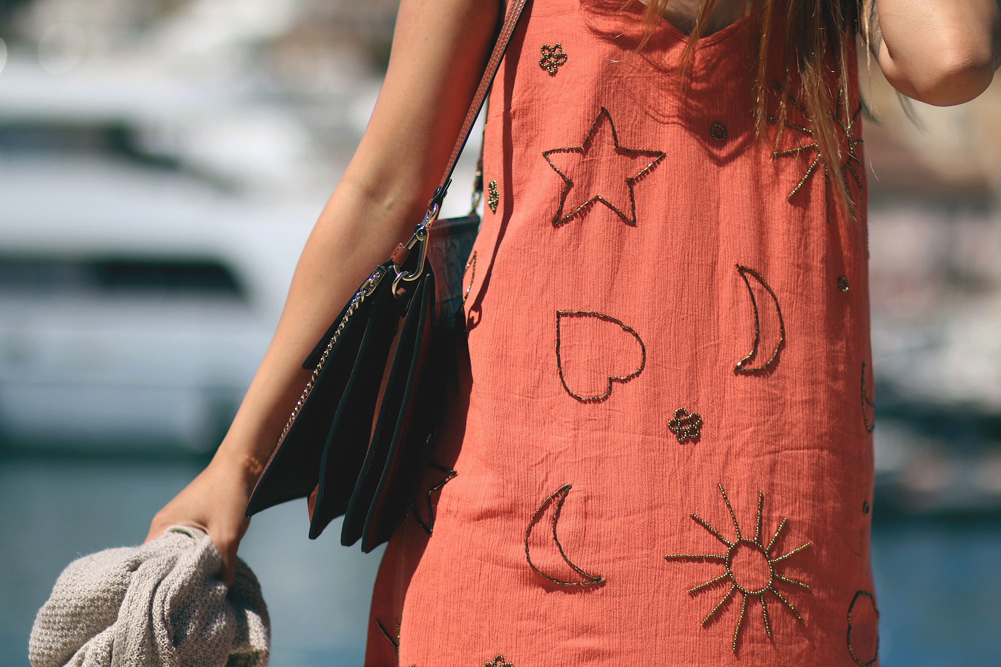 Desi is wearing: Embellished summer dress, cardigan, Cloé Faye bag, Hemès Oran Sandals, Ray-Ban Wayfarer sunglasses