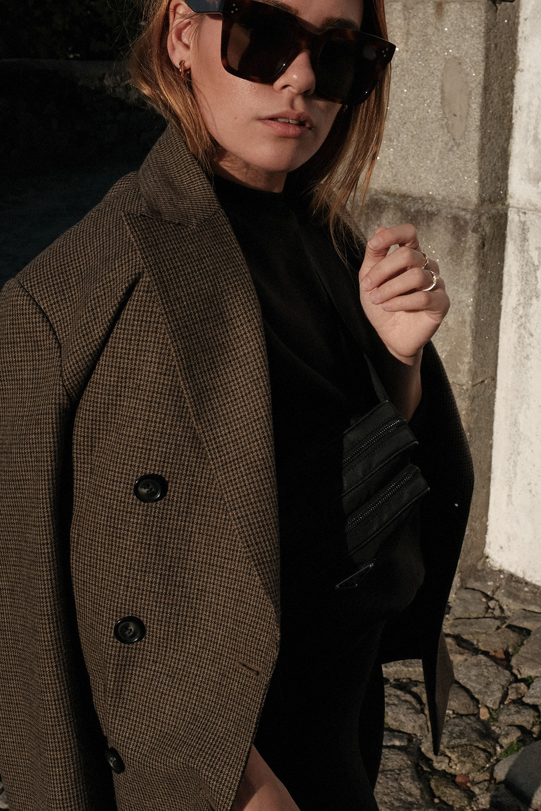 Desi is wearing an oversized blazer, Fruit of the Loom jumper, Lululemon leggings, New Balance 991 sneakers, Céline Tilda sunglasses Prada belt bag in Porto