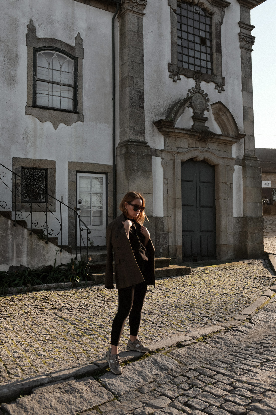 Desi is wearing an oversized blazer, Fruit of the Loom jumper, Lululemon leggings, New Balance 991 sneakers, Céline Tilda sunglasses Prada belt bag in Porto