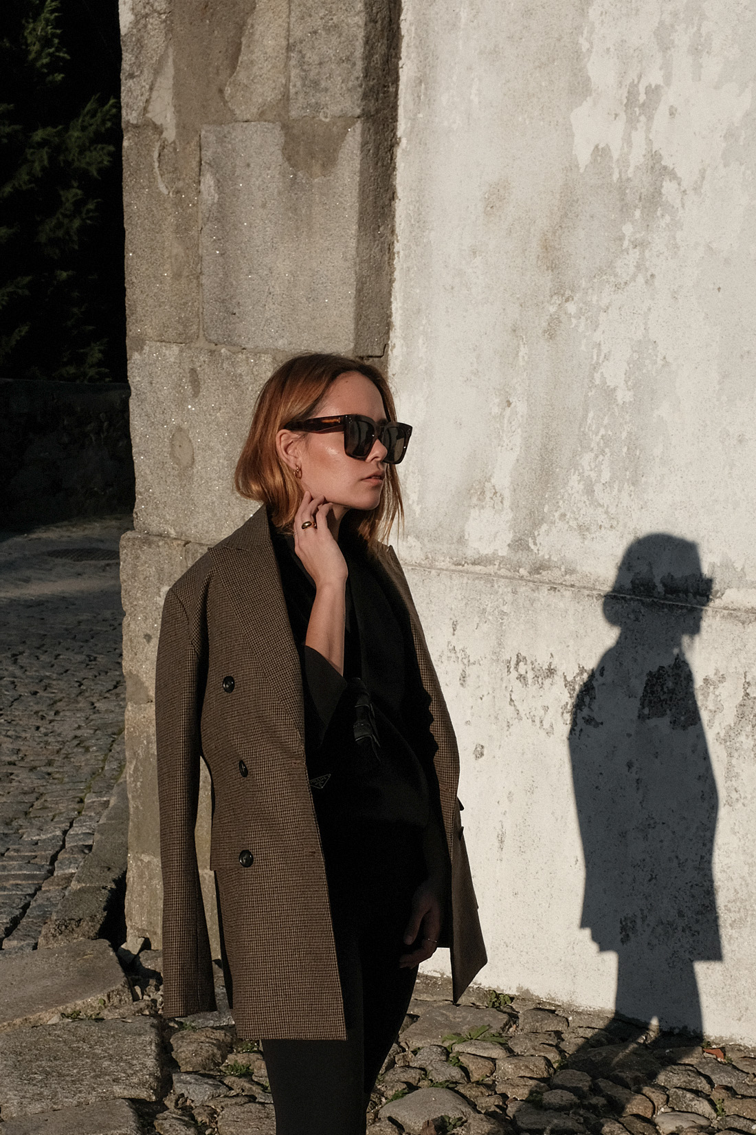 Desi is wearing an oversized blazer, Fruit of the Loom jumper, Lululemon leggings, New Balance 991 sneakers, Céline Tilda sunglasses Prada belt bag in Porto