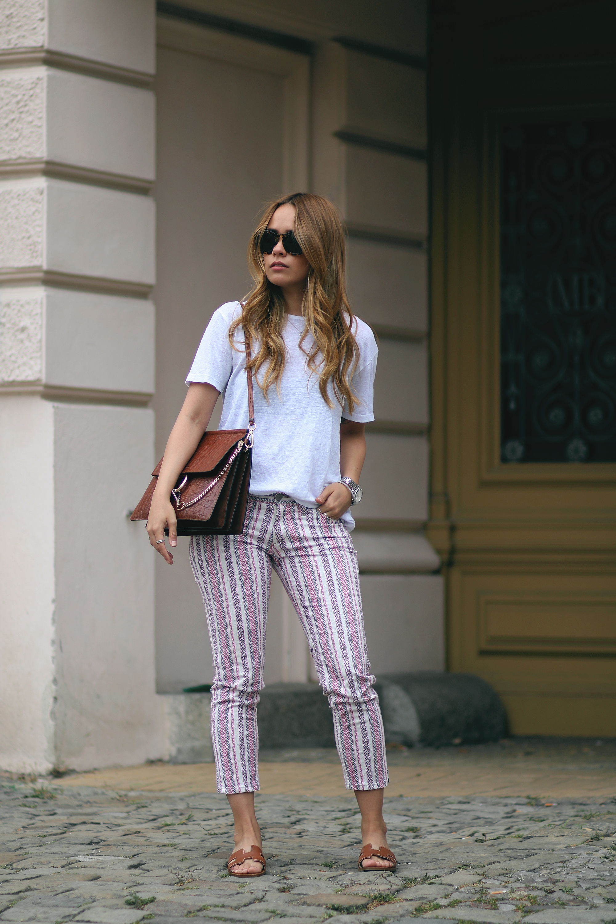 Desi wearing: Isabel Marant Étoile Printed trousers, Hermès Oran sandals, Chloé Faye bag, Céline Sunglasses, white linen shirt, boyfriend watch