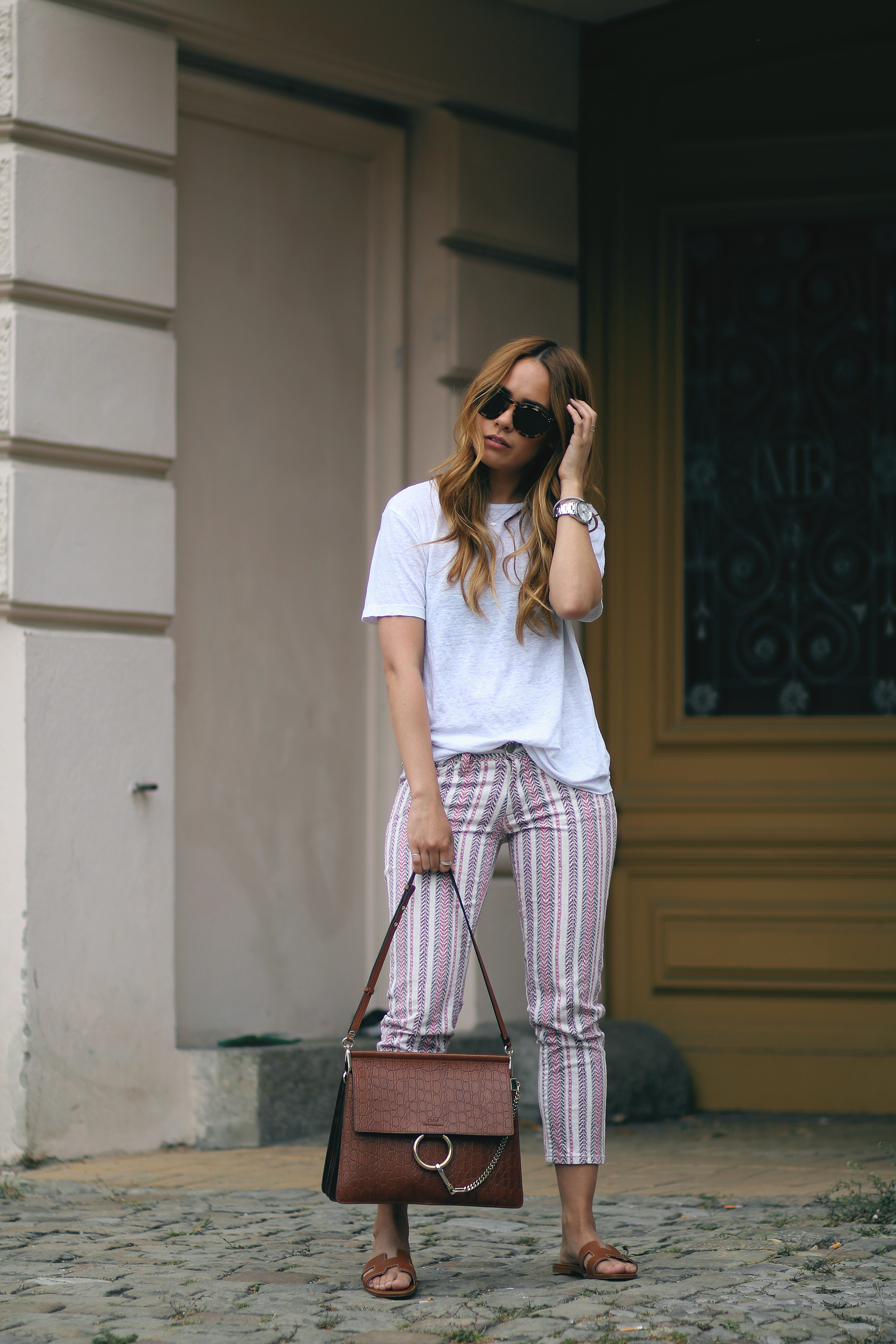 Desi wearing: Isabel Marant Étoile Printed trousers, Hermès Oran sandals, Chloé Faye bag, Céline Sunglasses, white linen shirt, boyfriend watch