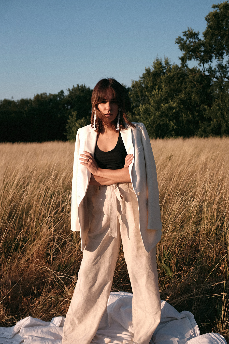Nisi is wearing: Uniqlo linen paperbag trousers, Arket White blazer, Chanelle black bralette, Mango white statement earrings