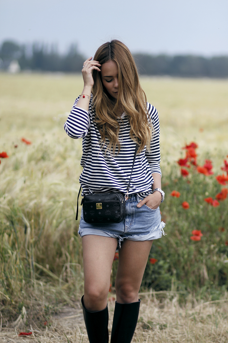 Desi is wearing a striped shirt, denim shorts, rubber boots and MCM bag