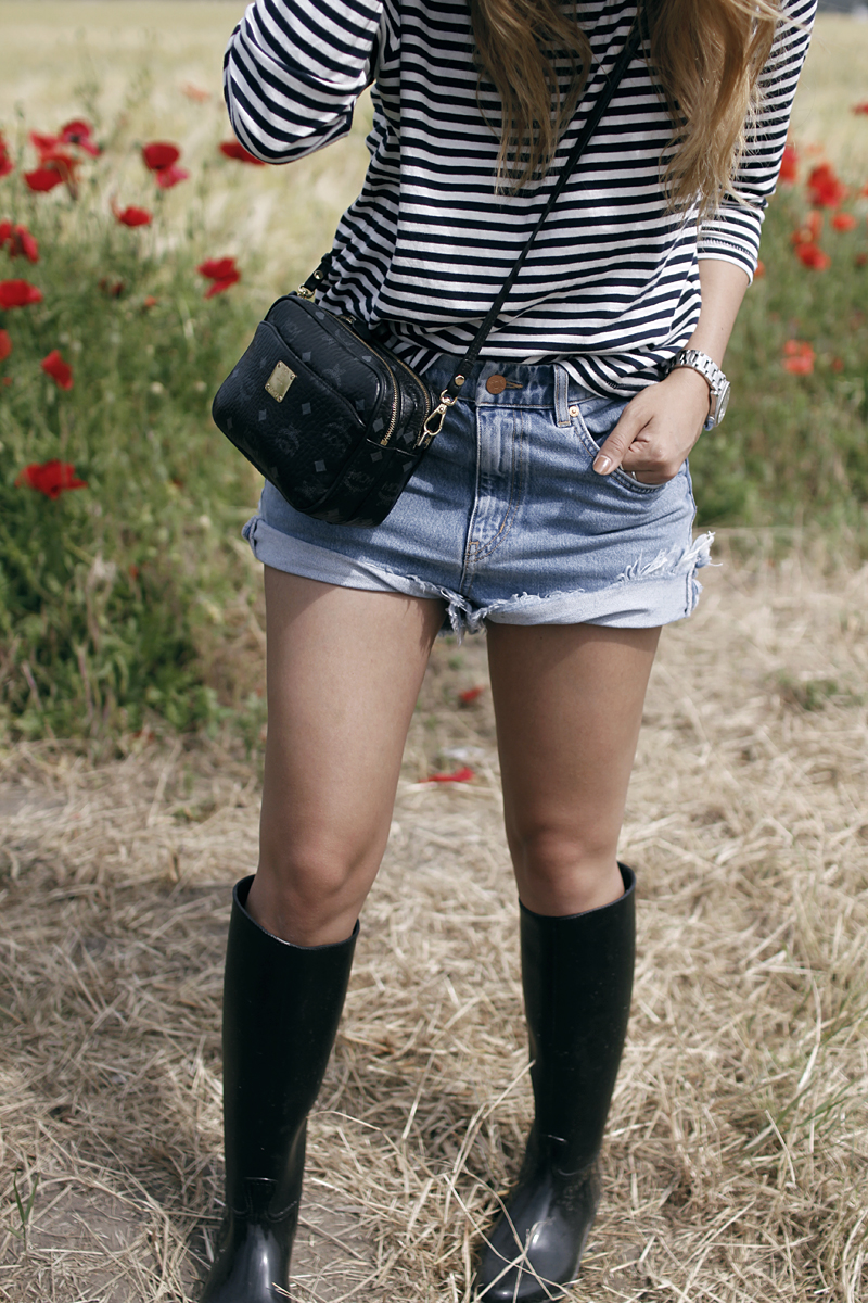 Desi is wearing a striped shirt, denim shorts, rubber boots and MCM bag