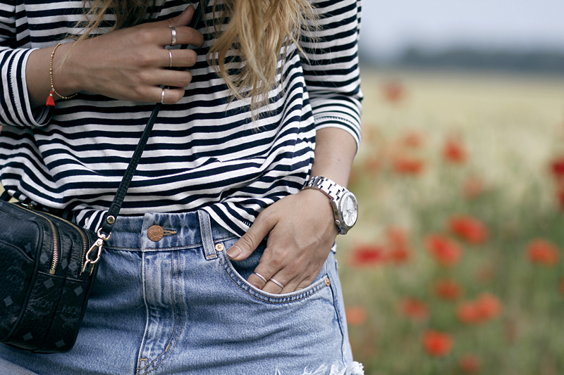 Desi is wearing a striped shirt, denim shorts, MCM bag and silver watch