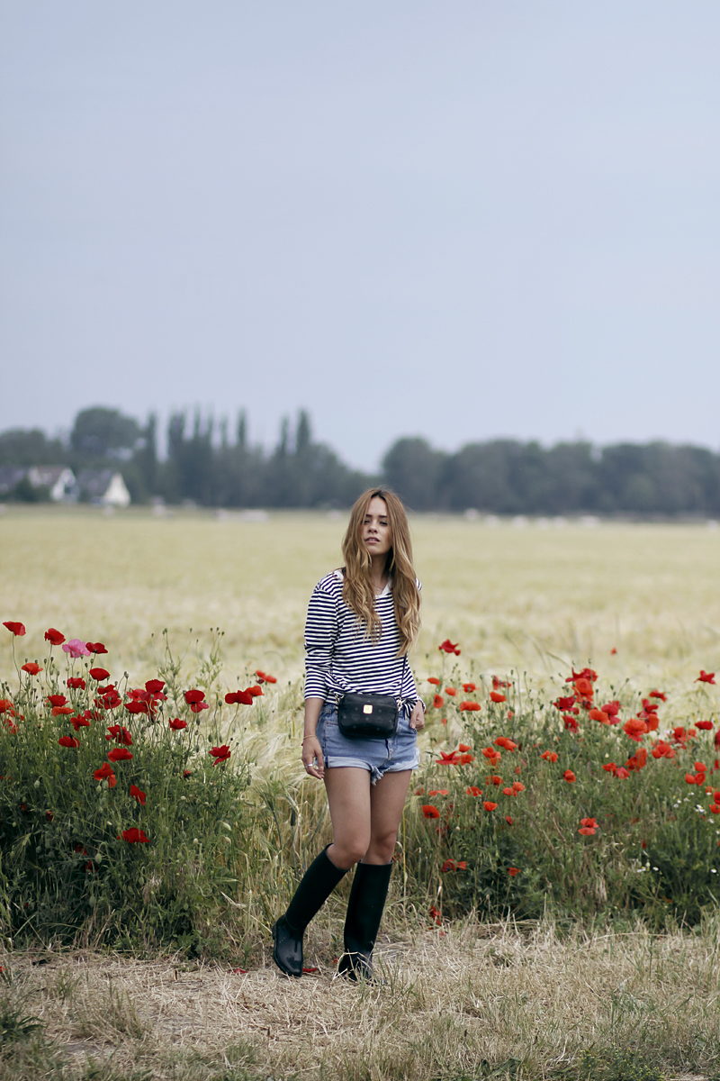 Desi is wearing a striped shirt, denim shorts, rubber boots and MCM bag