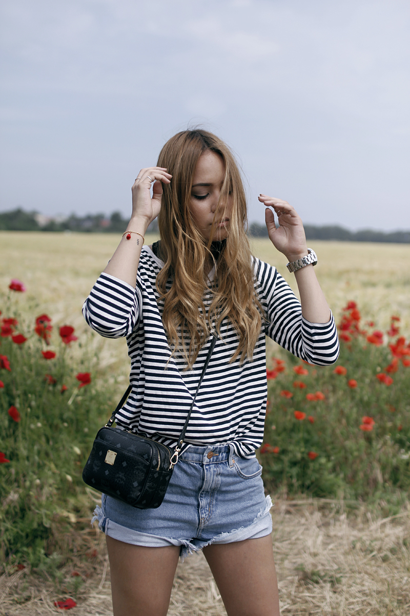 Desi is wearing a striped shirt, denim shorts and MCM bag