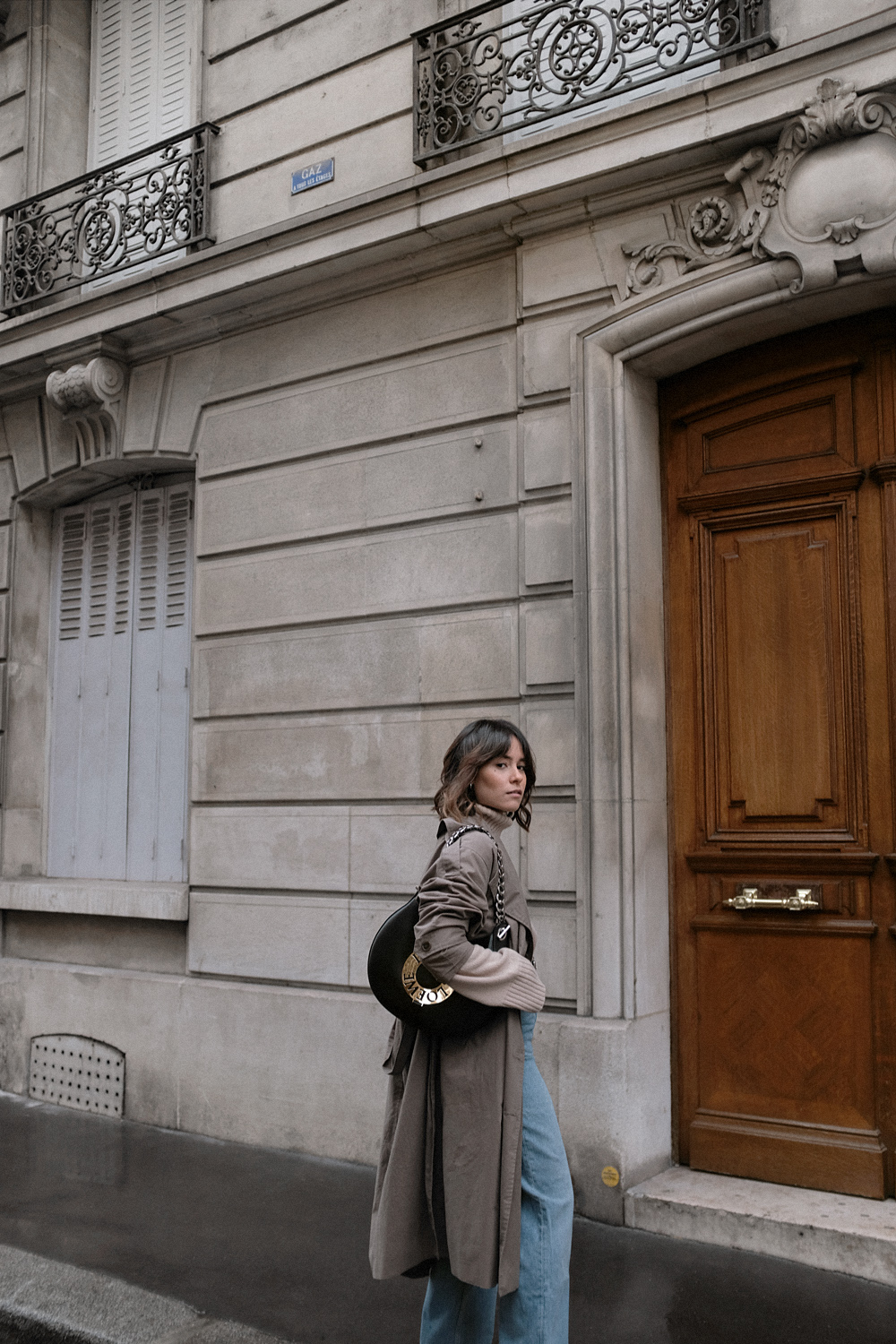 Nisi is wearing: Loewe Joyce bag, Céline Green Suede Boots, Trenchcoat, Turtleneck sweater, Wide denim jeans, L’Or Liquide Mini hoops