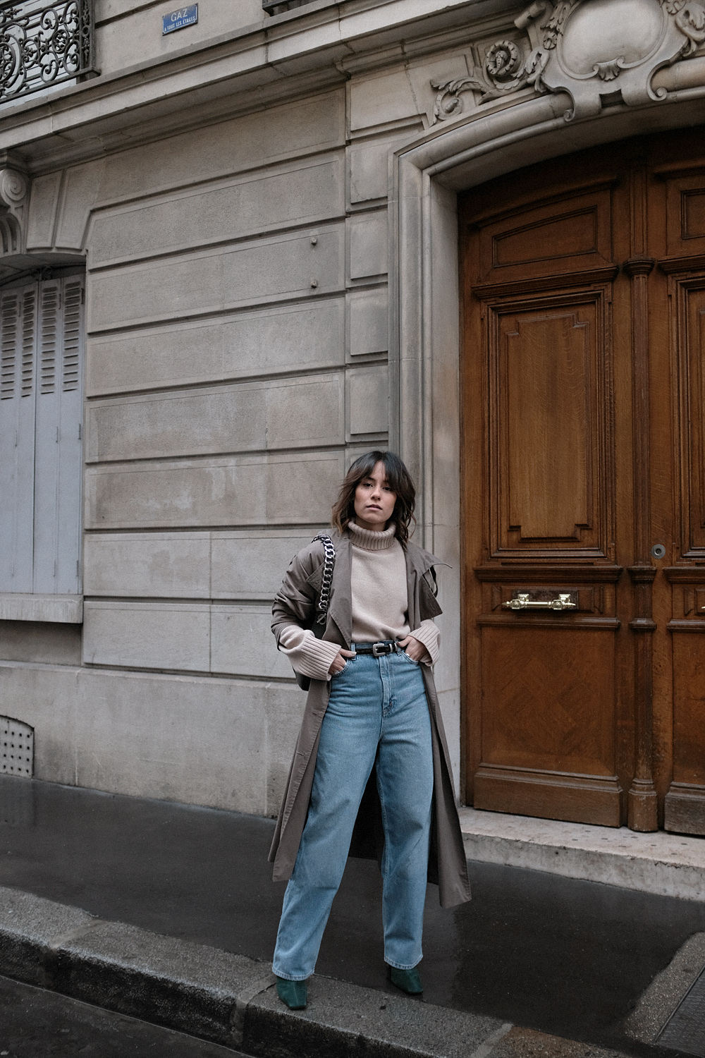 Nisi is wearing: Loewe Joyce bag, Céline Green Suede Boots, Trenchcoat, Turtleneck sweater, Wide denim jeans, L’Or Liquide Mini hoops