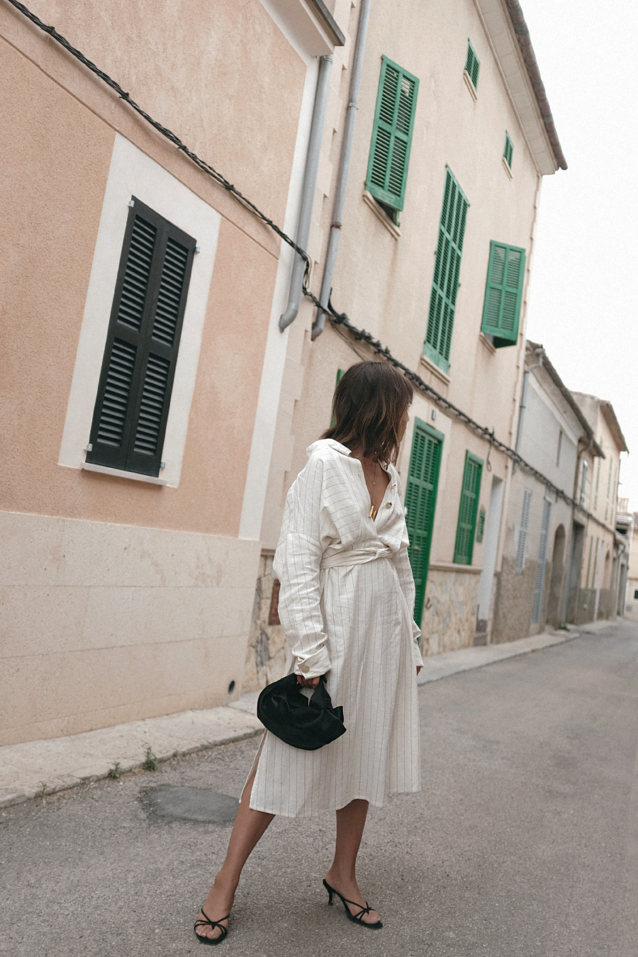 Nisi is wearing: The Row Ascot bag,  Céline Alphabet necklace, Striped dress, Black strappy sandals, Coral necklace, Gold pearl earring