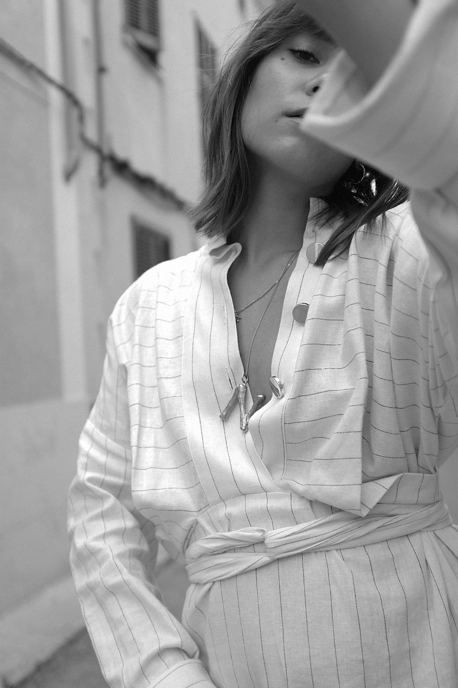 Nisi is wearing: The Row Ascot bag,  Céline Alphabet necklace, Striped dress, Black strappy sandals, Coral necklace, Gold pearl earring