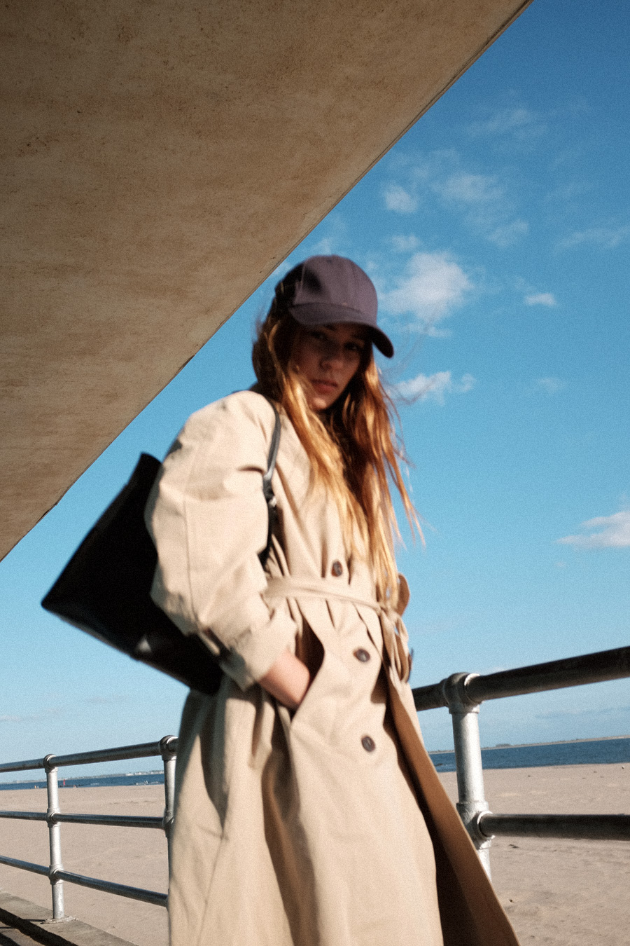 Outfit: Trenchcoat and Daddy Cap. Desi is wearing: Boyy Devon Bag, New Era Daddy cap, Trenchcoat – Moible, Mom jeans, Club C 85 Vintage Reebok Sneakers